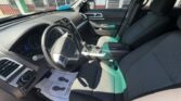 Interior of a dark-gray SUV showing the driver area, steering wheel, center console, and front seats in view at a dealership.