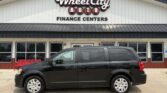 Black minivan parked in front of Wheel City Auto Finance Centers storefront.