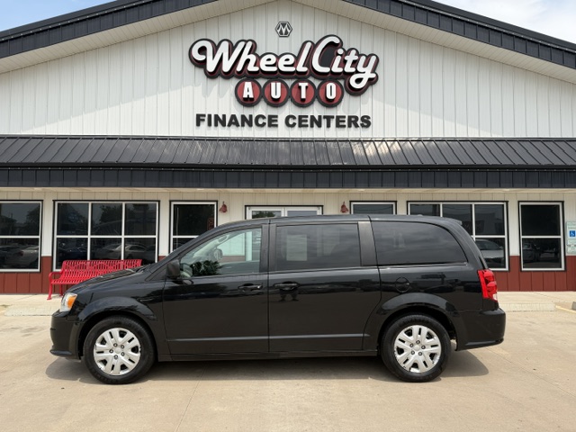 Black minivan parked in front of Wheel City Auto Finance Centers storefront.