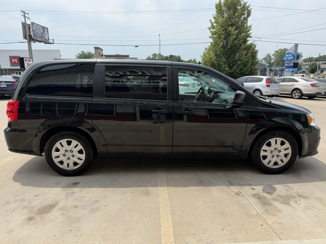 Black minivan parked in a parking lot, shown in profile with sliding side door and tinted windows.