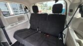 Interior of a white minivan showing a black three-person rear bench seat with three headrests and seat belts.