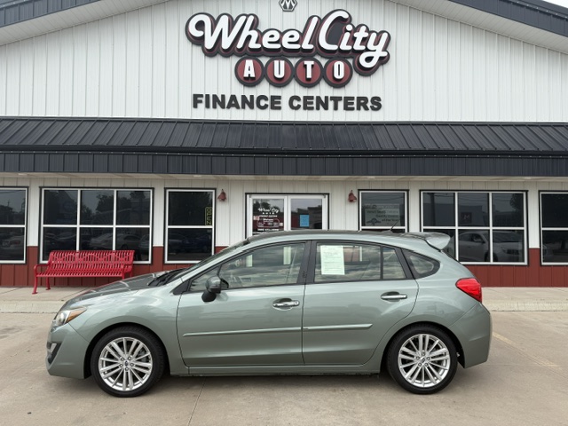 Mint-green hatchback parked in front of Wheel City Auto Finance Centers storefront signs visible above the building front.
