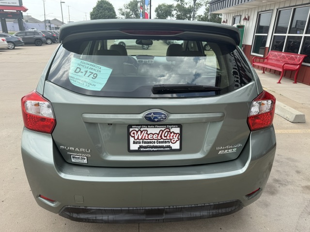 Rear view of a gray Subaru Impreza hatchback at a dealership, with a Wheel City Auto Finance Centers license plate frame and a D-179 window sticker on the rear window.