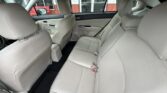 Light beige leather rear car seats with three seat belts, upright headrests, and a center armrest in a sedan interior.