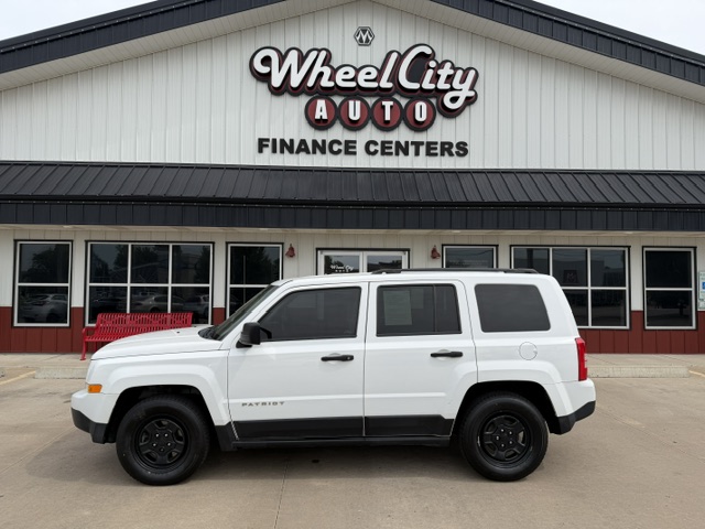 White Jeep Patriot SUV parked in front of Wheel City Auto Finance Centers storefront.