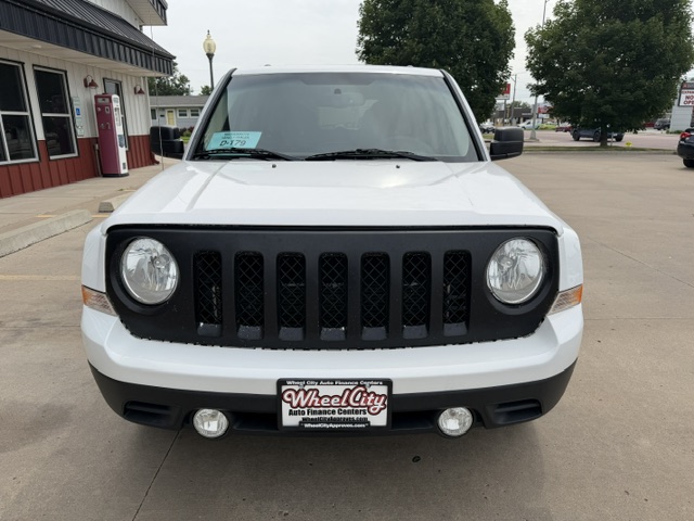Front view of a white SUV with a black seven-slot grille and round headlights, parked at Wheel City Auto Finance Centers.