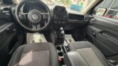 Front interior of a Jeep showing the steering wheel, center console, and two front cloth seats as seen from the rear seat area