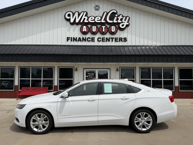 White four-door sedan parked in front of Wheel City Auto Finance Centers storefronts sign on the building