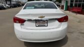 White Chevrolet sedan parked in a dealership lot, rear view with LT badge and Wheel City license plate frame on the dealer plate.