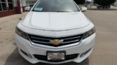 Front view of a white Chevrolet SUV parked at a dealership, showing the chrome grille and gold bowtie badge.