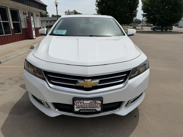 Front view of a white Chevrolet SUV parked at a dealership, showing the chrome grille and gold bowtie badge.