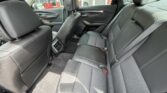 Rear interior of a gray car showing three-seat bench with headrests and seat belts in the back row at dusk light coming through the windows.