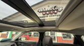 View from inside a car with a panoramic sunroof, looking at a Wheel City Auto Finance Center building through the roof opening.