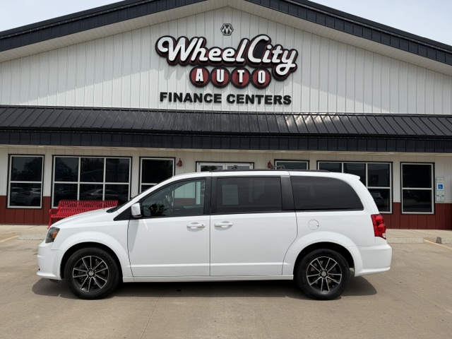 White minivan parked in front of WheelCity Auto Finance Centers storefront on a sunny day.