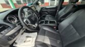 Interior of a Honda SUV showing black leather front seats, steering wheel, dashboard, center console with cup holders, and a dealership floor mat on the driver's side.