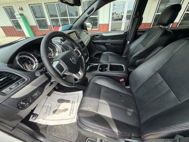 Interior of a Honda SUV showing black leather front seats, steering wheel, dashboard, center console with cup holders, and a dealership floor mat on the driver's side.