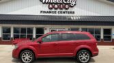Red SUV parked in front of Wheel City Auto Finance Centers storefront with beige building and large sign above the entrance.