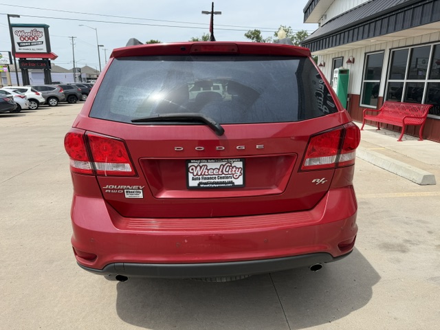 Red Dodge Journey SUV seen from the back in a car dealership lot, with Wheel City Auto Finance Centers license plate frame.