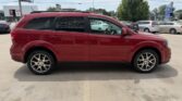 Red SUV parked in a dealership lot, side view showing four doors and alloy wheels with tinted windows