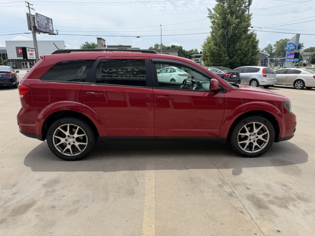 Red SUV parked in a dealership lot, side view showing four doors and alloy wheels with tinted windows
