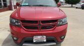Front view of a red Dodge SUV parked in a lot, showing its crosshair grille, headlights, and a Wheel City Auto Finance Centers license plate frame on the bumper.