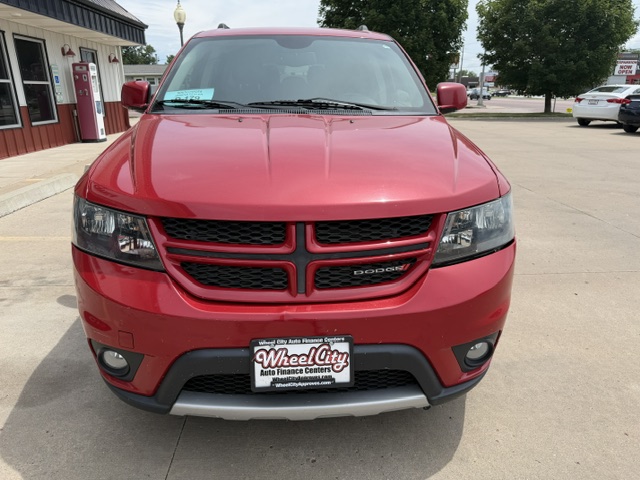 Front view of a red Dodge SUV parked in a lot, showing its crosshair grille, headlights, and a Wheel City Auto Finance Centers license plate frame on the bumper.