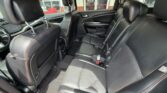 Back seat interior of a black leather SUV with red contrast stitching and three seats, visible headrests and seat belts.