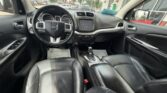 Front interior of a black leather car, shown from the back seats with steering wheel, dashboard, and center console visible.
