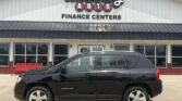 Black Chevrolet Compass SUV parked in front of Wheel City Auto Finance Centers storefront, with a red bench visible to the left.