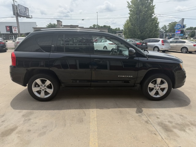Side view of a black SUV parked in a car dealership lot with other vehicles in the background.