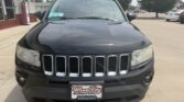 Front view of a black Jeep SUV in a parking lot, showing the seven-slot grille and Wheel City Auto Finance Centers license plate.