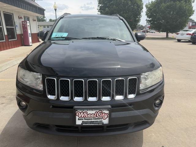 Front view of a black Jeep SUV in a parking lot, showing the seven-slot grille and Wheel City Auto Finance Centers license plate.