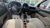 Front cabin view of a beige-cloth interior SUV with a black steering wheel, central touchscreen, and gear shifter in focus, showing a clean dashboard setup.