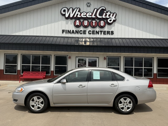 Silver sedan parked in front of a Wheel City Auto Finance Centers building; dealership sign visible above the entrance