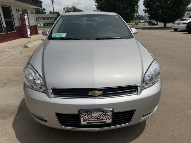 Front view of a silver Chevrolet sedan parked in a lot, with a Wheel City license plate frame visible on the front bumper.