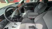 Interior view of a gray cloth-seat car cabin with wood trim, showing the steering wheel, dashboard, center console, and front seats from the driver's side to the passenger side.