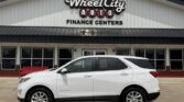 White Chevrolet Equinox SUV parked in front of Wheel City Auto Finance Centers storefront, with the dealership sign visible.