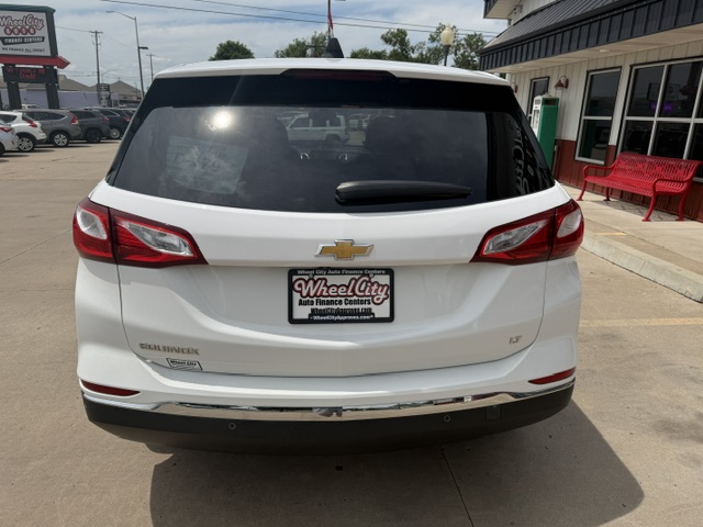 Rear view of a white Chevy SUV in a parking lot, displaying dealership plate frame 'Wheel City Auto Finance Centers'.