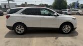 Side view of a white Chevrolet Equinox SUV parked in a car dealership lot with other vehicles in the background.