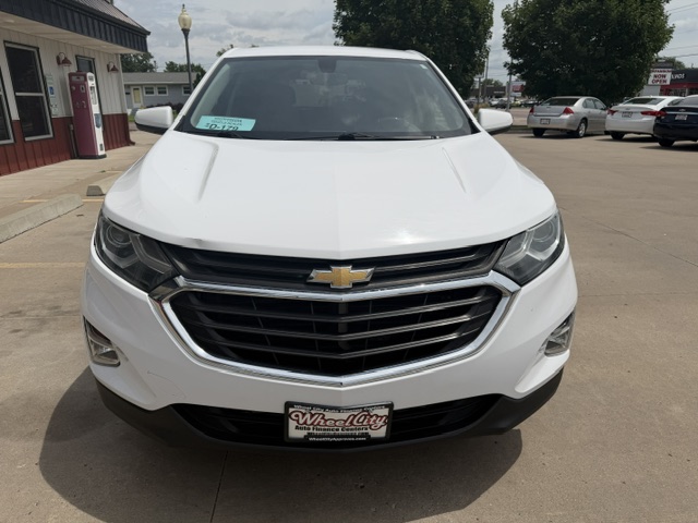 Front view of a white Chevrolet SUV in a dealership lot, showing the prominent grille and Chevrolet bow-tie badge with a dealer plate on the bumper.