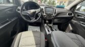 Interior of a Chevrolet car: steering wheel with bowtie emblem, center touchscreen, gear shifter, and front seats visible from the back seat.