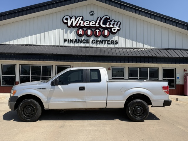 Silver Ford F-150 pickup truck parked in front of Wheel City Auto Finance Centers storefront.