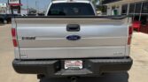 Rear view of a silver Ford F-150 pickup, showing the Ford emblem and F-150 badge on the tailgate and a dealership plate on the bumper.