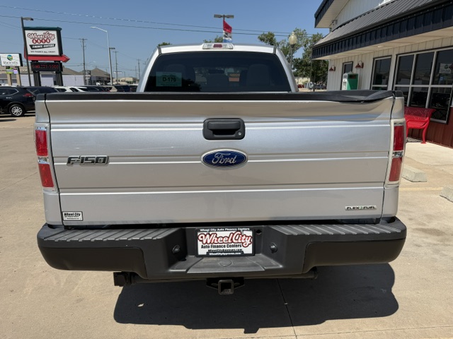 Rear view of a silver Ford F-150 pickup, showing the Ford emblem and F-150 badge on the tailgate and a dealership plate on the bumper.