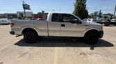 Side profile of a white Ford F-150 pickup with extended cab, parked in a sunny parking lot.