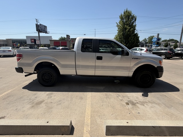 Side profile of a white Ford F-150 pickup with extended cab, parked in a sunny parking lot.