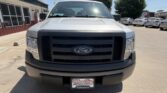 Front view of a silver Ford pickup truck in a car dealership lot, with a black grille and Ford emblem visible on the grille.
