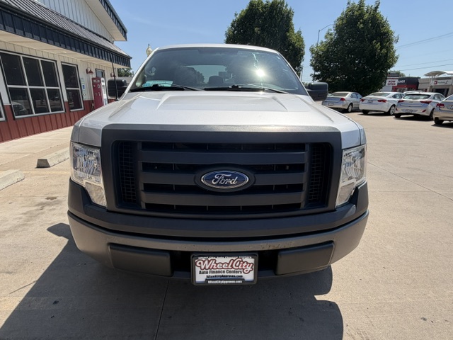 Front view of a silver Ford pickup truck in a car dealership lot, with a black grille and Ford emblem visible on the grille.