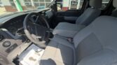 Interior of a gray pickup truck: driver seat, steering wheel, and front passenger seat seen from the driver's side.