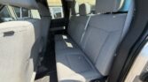 Rear bench seat in a gray fabric car interior with three seat belts and front seats visible